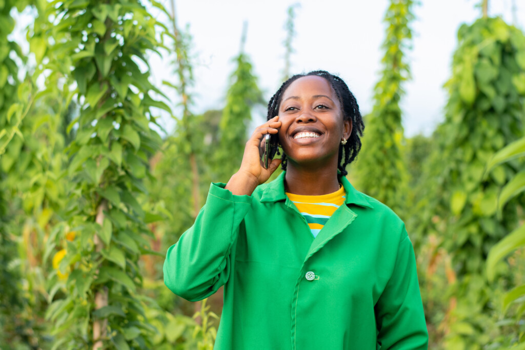 A cheerful African farmer talking on the phone while working on the field
